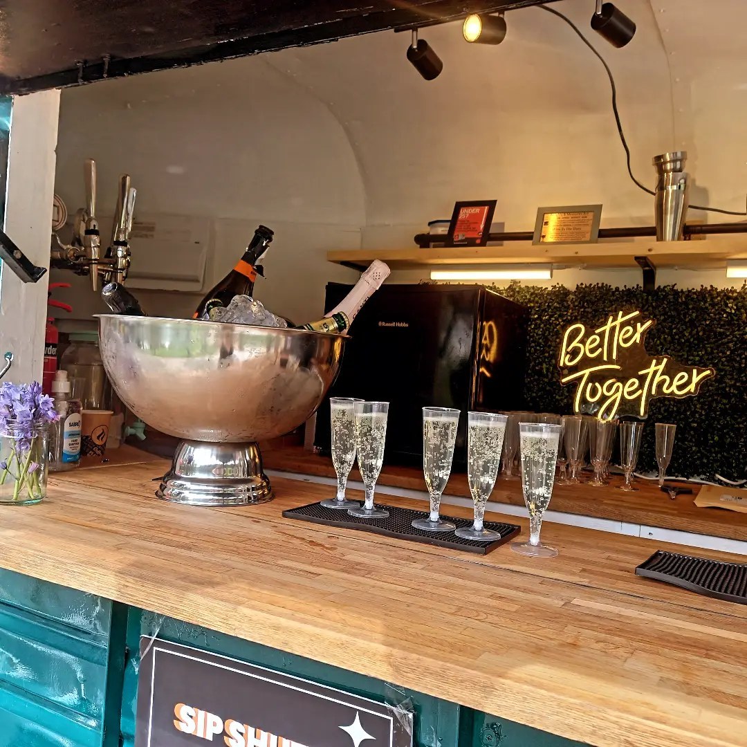 Champagne flutes and neon Better Together sign inside the bar