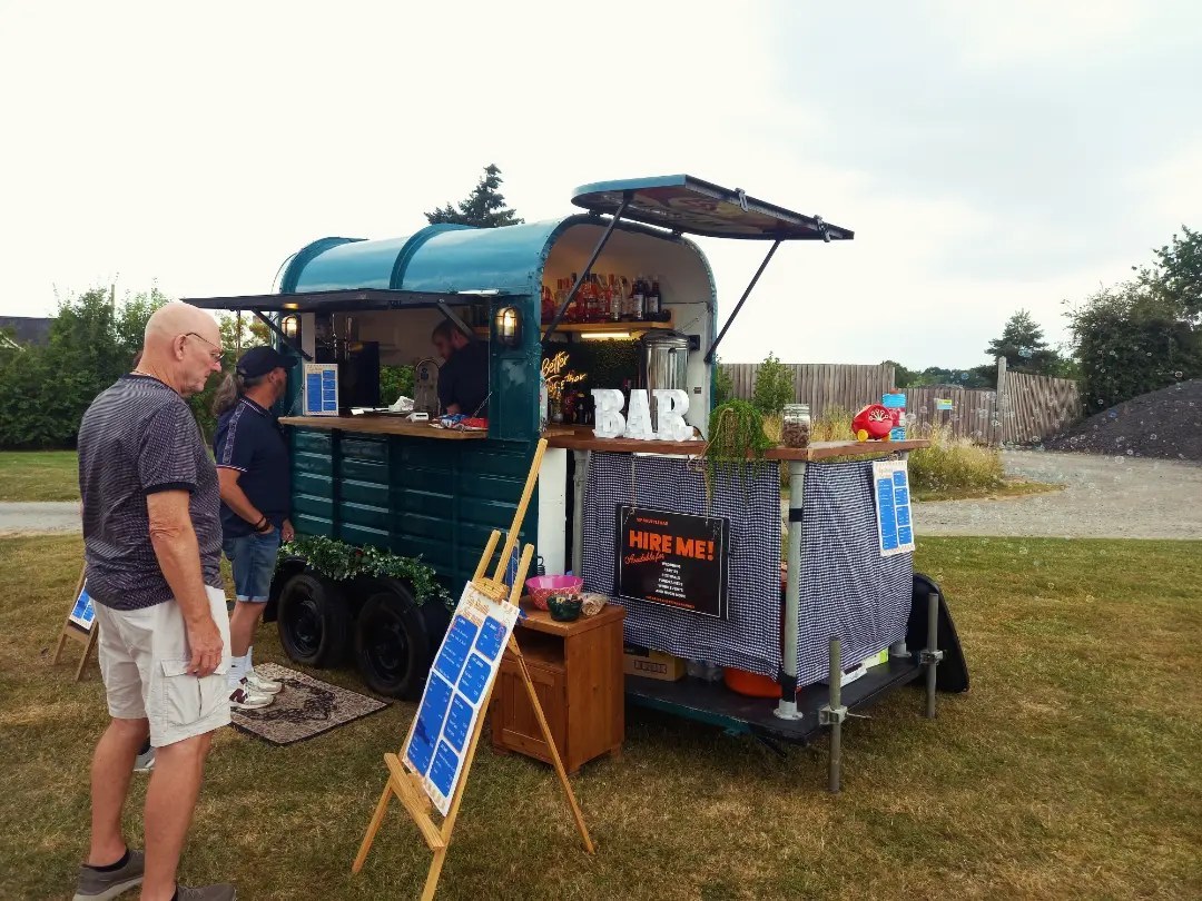 Sip Shuttle Bar serving guests outdoors with menus and Hire Me sign